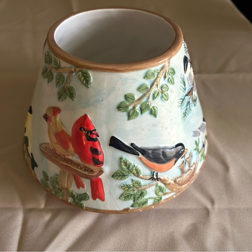 Ceramic candle holder or shade featuring embossed bird designs. Has chip on rim